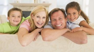 Family sitting in living room smiling